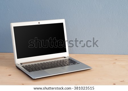 Office desk Notebook on wooden floor and blue cement background. View from  above with computer screen.