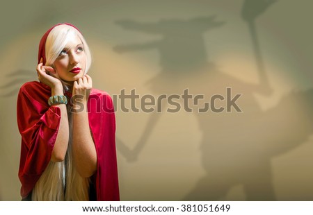 young lady in red hooded cape and wolf shadow on wall