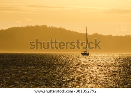 Sailing boat tourism parking on the sea in the morning at orange sunset sky and silhouette island background, travel tourism concept present.