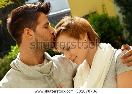 Closeup photo of embracing loving couple. Man kissing girlfriend.