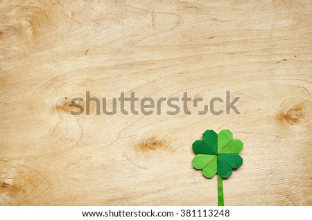 Origami paper green clover shamrock leaf on light plywood background. Space for copy, text, lettering.