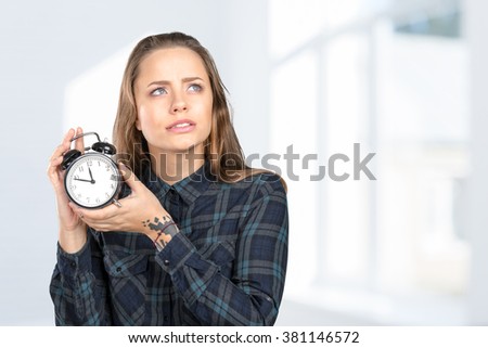 Young woman holds an alarm clock in front of herself
