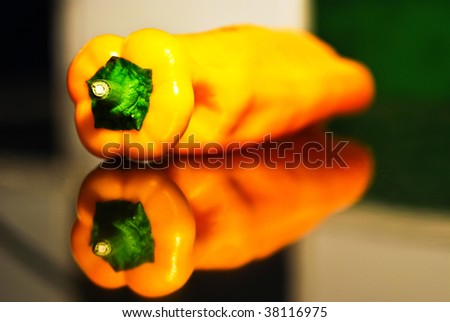 Picture of yellow pepper laying on a reflecting surface