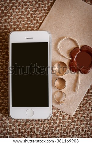 mobile phone and gold rings on envelope in wedding day