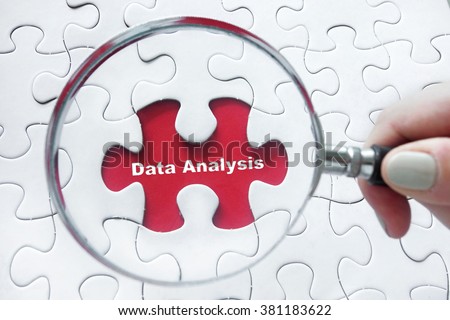 Word Data Analysis with hand holding magnifying glass over jigsaw puzzle Royalty-Free Stock Photo #381183622