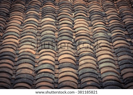 Close-up view curved clay tiled roof in various colors from an old house in North Vietnam, late afternoon light. Ancient, weathered roof tile surface and moss. Natural seamless pattern. Vintage look.