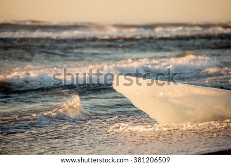 An ice fragment on the Jokulsatlon Beach wit the string ocean waves in background. It reminds me of the Pride Rock in the animation, The Lion King.