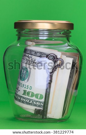 Money in glass jars, on Green background