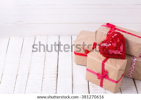 Festive gift boxes and red decorative heart  on white wooden background. Selective focus. Place for text.