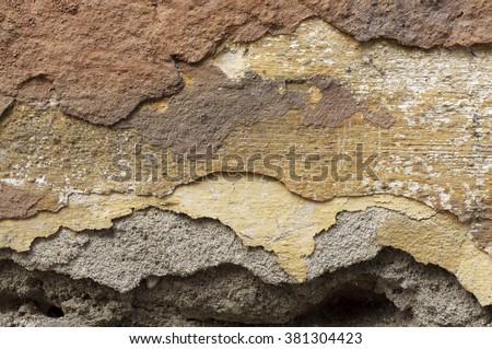 Close up of old, crumbling,cracked, grunge brick mortar  wall 
Several layers of peeled  orange, beige, brown,grey and ocher facade  paint  
Detail abstract texture background ,space for  text, copy
