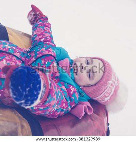 Cute kid riding snow tube winter day. Photos in retro style.