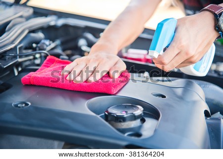 Wipe cleaning the car engine with red microfiber cloth 