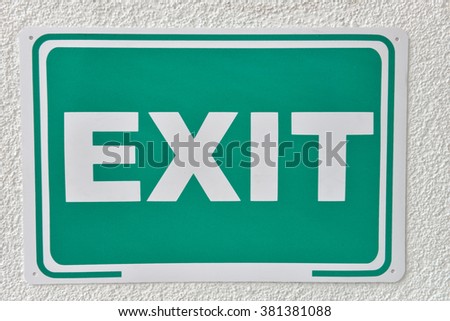Green emergency exit sign on a wall. Label that will help you escape