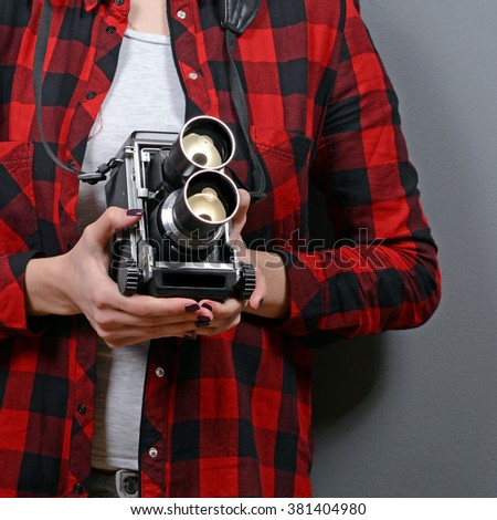 Portrait of hipster girl with retro camera against gray background