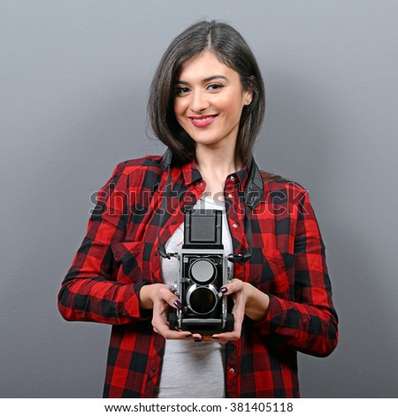 Portrait of hipster girl with retro camera against gray background