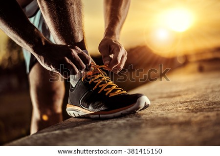Man tying jogging shoes Royalty-Free Stock Photo #381415150