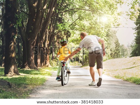 Father help his son ride a bicycle Royalty-Free Stock Photo #381418033