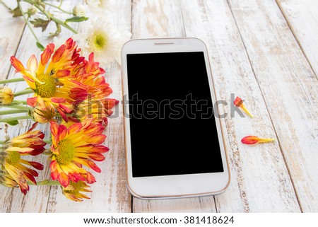 Smart phone and fresh flowers on white wood table background