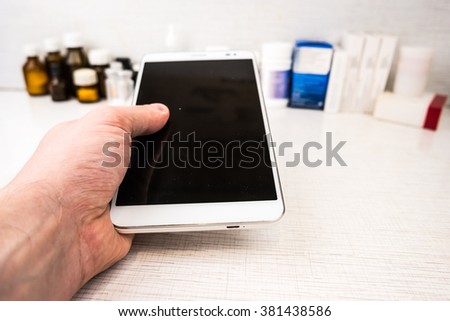 Tablet pc in hands of a doctor with medical objects on white table as an image for electronic diagnostic or healthcare mobile apps. Medical background