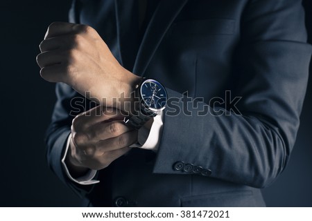Businessman checking time from watch Royalty-Free Stock Photo #381472021