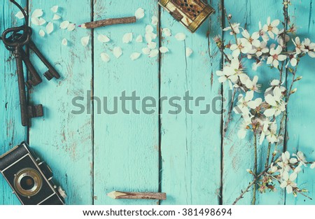 top view image of spring white cherry blossoms tree, old camera on blue wooden table. vintage filtered and toned
