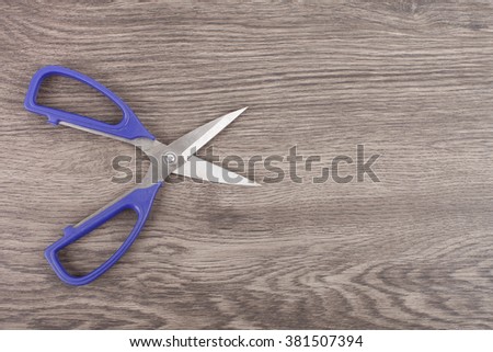 Open Pair of Scissors on wood Background.