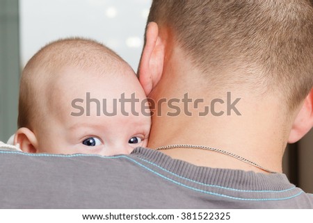 Portrait of a beautiful white blue-eyed newborn baby in the hands of Dad close up