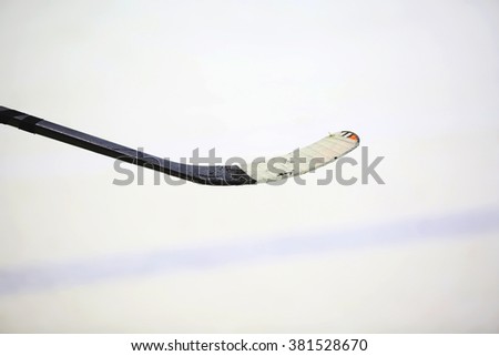 A taped and used hockey stick on a background of play ground of ice hall