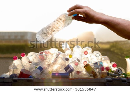 Hand holding recyclable plastic bottle in garbage bin environment conceptual. Royalty-Free Stock Photo #381535849
