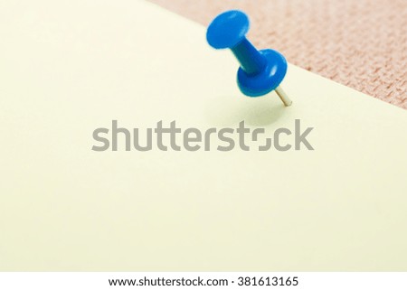 Adhesive note and blue pushpin. Close-up view