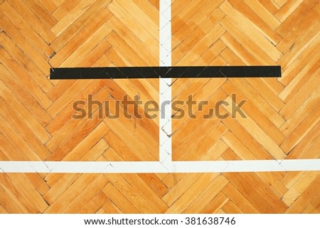 Black and white lines in playground. Worn out brown wooden floor of sports hall with colorful marking lines.