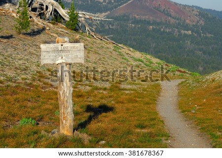 Wooden trail pointer with mountains in the background. At South Sister near Moraine lake, Central Oregon, USA Pacific Northwest.