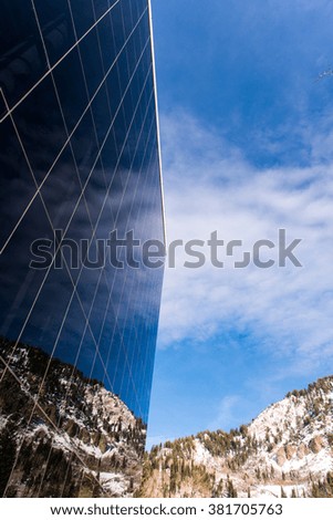 Large Blue Glass windows reflecting a deep blue from the sky with a rocky mountain as the background