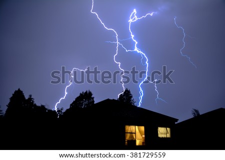 Cloud to Ground Urban Lightning, Lighting Up House Rooftops in the City Night Skies. Royalty-Free Stock Photo #381729559