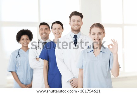 international, profession, people and medicine concept - group of happy doctors and nurses at hospital showing ok hand sign