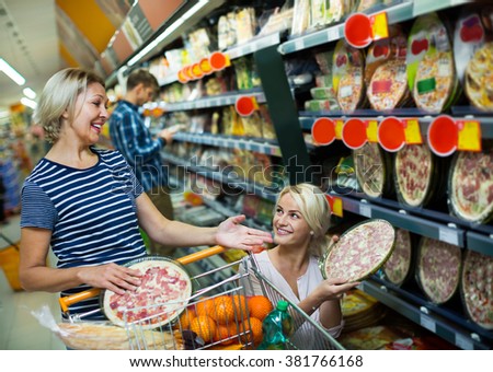 Adult girl helping senior mother in a pizza section of a supermarket 