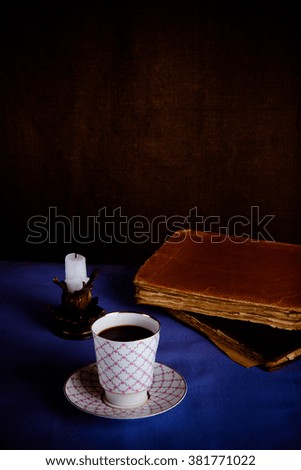 Old books, cup of coffee, candy and ancient candle on the table. Selective focus. Toned.