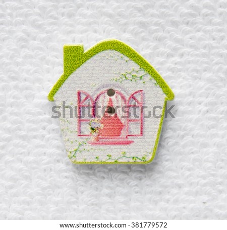 Beautiful wood buttons from wood in the shape of a house on a light background. Button closeup in the form of a house with the Windows open