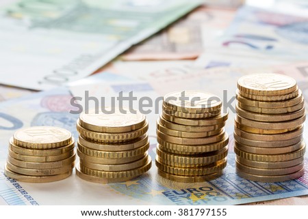 Stack of ascending Euro coins on banknote money background