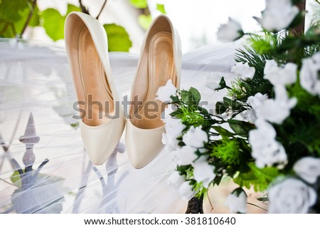White wedding shoes on fatin with artificial flowers