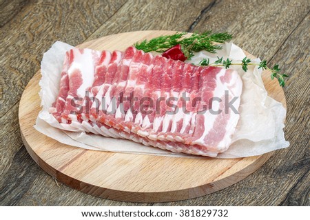 Raw sliced bacon ready for cooking on wood background