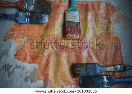 old paint brush on Kraft paper and red and yellow acrylic paint