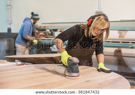 Female carpenter Using Electric Sander for wood Royalty-Free Stock Photo #381847432