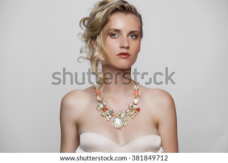 Young beautiful blond girl with a wedding hairstyle. Portrait of the bride on gray  background isolated