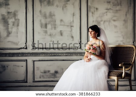 Young bride is sitting in an armchair. Beautiful Bride Portrait wedding makeup, wedding hairstyle, Wedding dress. Wedding decoration. soft selective focus. gorgeous young bride at interior