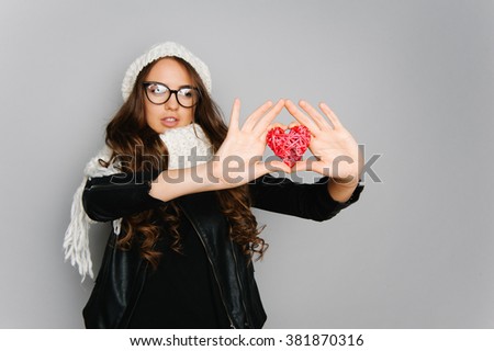 Portrait of cute teen girl with heart in her hand isolated on gray studio background posing to the camera 