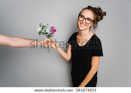 Portrait of cute teen girl with a bucket of flowers on gray studio background posing to the camera 

