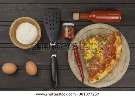 Homemade pizza. Portions of pizza on a dark wooden table. Food preparation.