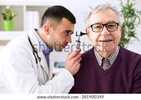 Doctor holding otoscope and examining senior patient ear Royalty-Free Stock Photo #381900349