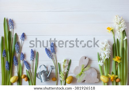 Easter white wooden background with flowers hyacinths, daffodils, eggs and rabbit, space for text